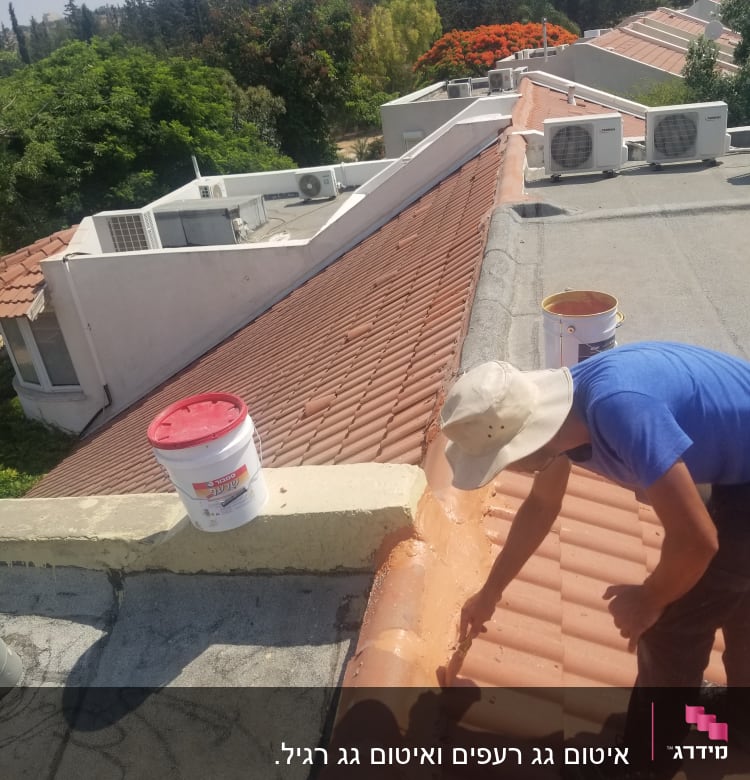 אדם מורח חומר על גג רעפים עם מברשת